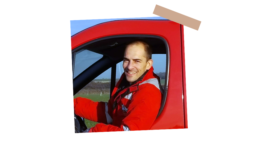 Franck Tuvache, franchisé Husse à Dijon, souriant à la fenêtre de son véhicule de service rouge.